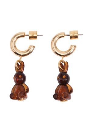 Pendientes de aro dorados con pequeños colgantes en forma de conejito color ámbar, mirando hacia adelante sobre un fondo blanco.