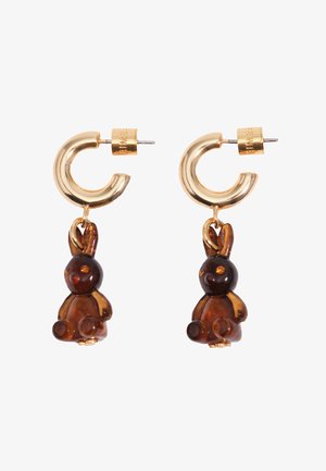Pendientes de aro dorados con pequeños colgantes en forma de conejito color ámbar, mirando hacia adelante sobre un fondo blanco.