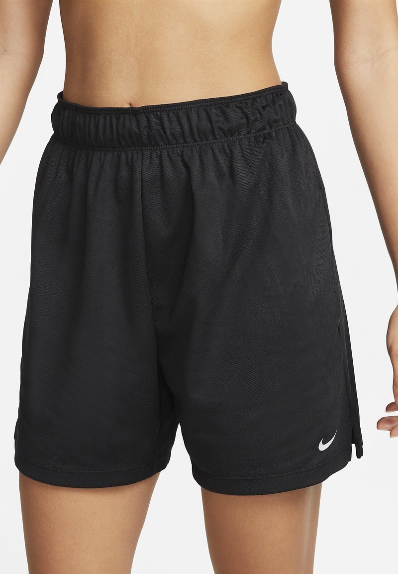 Personne portant un short de sport Nike noir à taille élastique, vue de la taille au milieu de la cuisse sur un fond blanc uni.