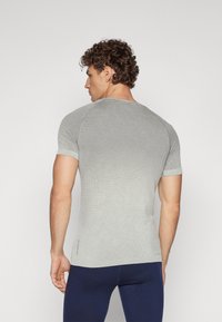 Camisa de manga curta cinza claro com um design texturizado em rede. Forma ajustada com decote redondo e um efeito de gradiente subtil na parte inferior.