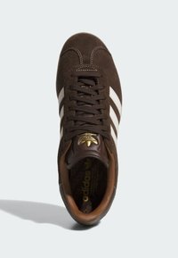 Baskets en daim marron avec des rayures blanches, accents en cuir marron, bout rond, lacets plats et détail du logo doré sur la languette.