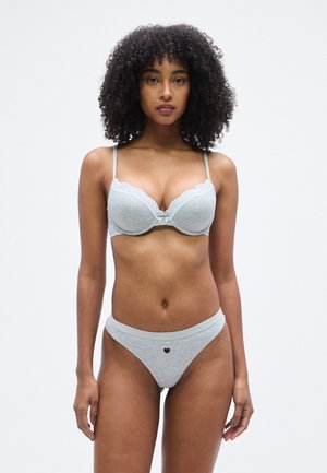 Ensemble de lingerie gris clair comprenant un soutien-gorge rembourré avec bordure en dentelle et détail en nœud, assorti à un string sans coutures orné d'un motif en forme de cœur.
