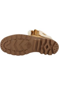 Botte en fourrure marron avec semelle en caoutchouc. Dispose d'une semelle extérieure texturée pour l'adhérence et d'une sangle avec des accessoires en métal. Doublure intérieure douce.
