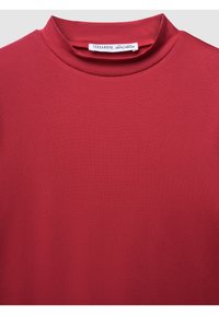 Maglietta rossa a collo alto con etichetta visibile che mostra il marchio Terranova e la taglia per età 12/13, altezza 152/158 cm.