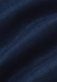 Ciemnoniebieska tkanina o gładkiej fakturze i subtelnym wzorze splotu, ukazująca fale, które sugerują miękkość i elastyczność.