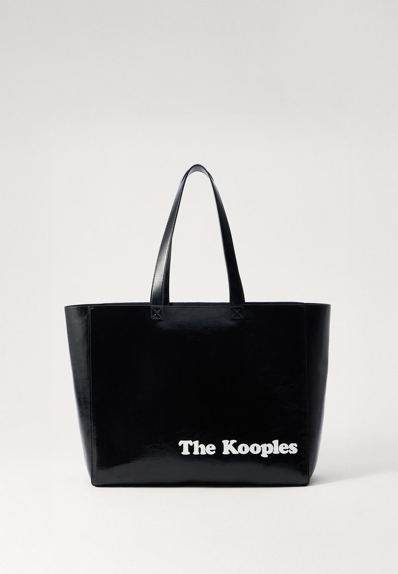 Sac cabas en cuir verni noir avec deux poignées, arborant le texte "The Kooples" en blanc en bas. Design structuré et minimal.