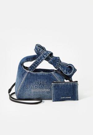Denim håndtaske med en knyttet håndtag, der har 'THE SACK BAG' prægning på forsiden og en matchende pung hængende ved en rem.