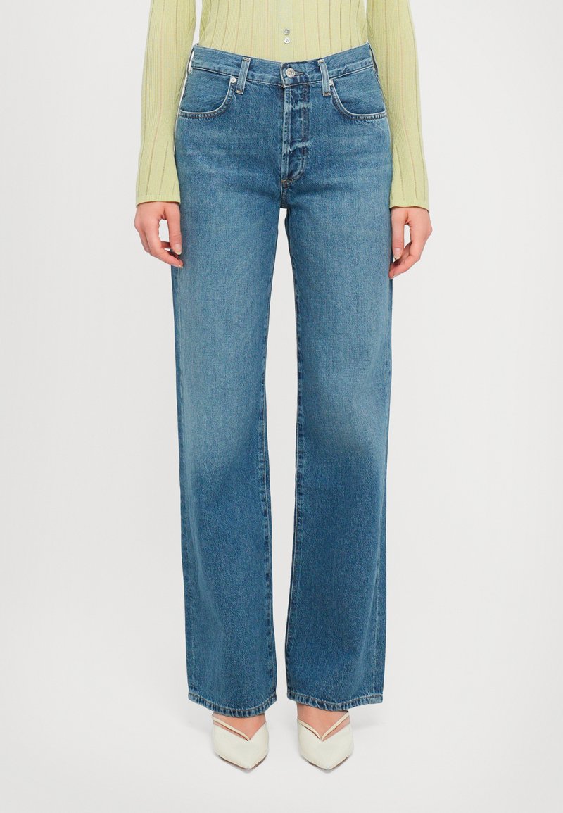 Wide-leg blue denim jeans with a high rise, featuring a button closure and classic pocket design. Smooth texture with slight fading details.