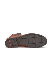 Brown leather shoe with a smooth upper, featuring a velcro strap and a textured black rubber sole with a red accent line.