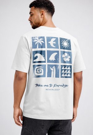 Man wearing white t-shirt with blue tropical icons in a 3x3 grid and text "Take me to Paradise" on the back, standing against a plain gray background.