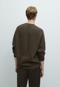 Dunkelbrauner gerippter Pullover mit Rundhalsausschnitt und langen Ärmeln, der einen lockeren Sitz und ein strukturiertes Strickdesign aufweist.