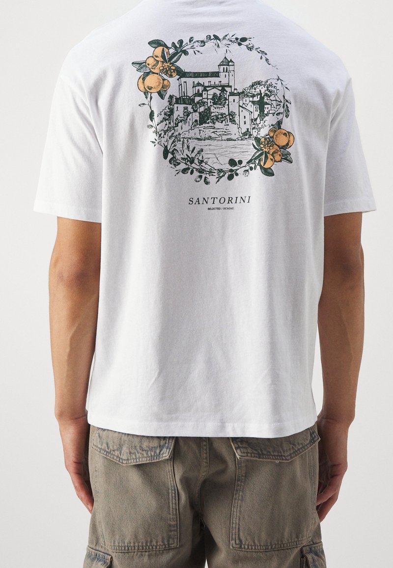 Bílé bavlněné tričko s grafikou Santorini a kulatým květinovým a oranžovým designem na zádech. Volný střih, krátké rukávy.