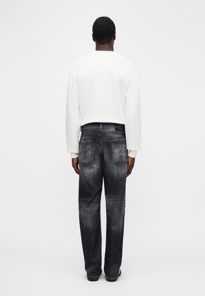 White cropped sweatshirt with long sleeves paired with dark, faded jeans featuring a slight wash effect and two back pockets.