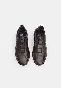 Black leather slip-on shoes with padded heel and elastic panel. Features sleek design with logo inside, smooth texture, and rounded toe.