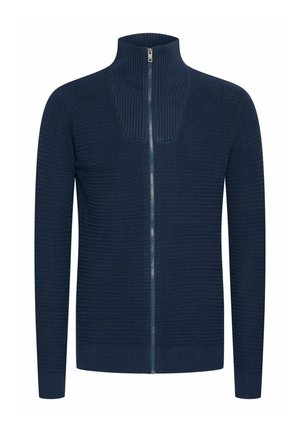 Marineblå hettegenser med glidelås laget av ribbestrikket stoff, med høy krage og subtil tekstur. Glidelås med en kontrasterende metallpull.