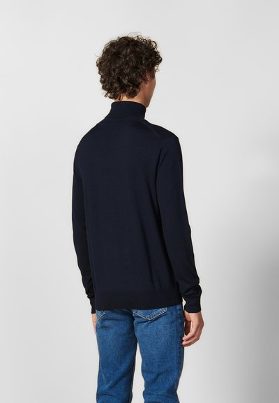 Maglione a collo alto blu marina realizzato in morbido tessuto a maglia, con una silhouette aderente e polsini a costine. La vista posteriore mostra dettagli minimali.