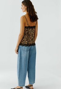 Leopardprint cami met zwarte kant, gecombineerd met hooggesneden, losse blauwe denim jeans en platte zwarte schoenen.