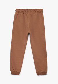 Brune sweatpants med elastisk talje, smalle cuffs og glat tekstur, der har et enkelt design uden mønstre eller accenter.