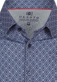 Marineblauwe shirt met bloemmotieven, met een knoopsluiting en een contrasterende lichte binnenkant van de kraag. Maat medium, gemaakt in Europa.