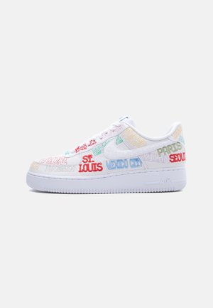 Zapatilla Nike Air Force 1 blanca con nombres de ciudades bordados en colores que cubren la parte superior y una suela blanca.