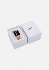 Smartwatch quadrato con display nero, bracciale in metallo a maglia dorata e confezione bianca con il nome del marchio LIU·JO in evidenza.