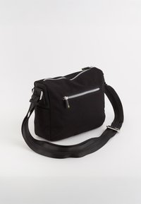 Sort stof crossbody tas med en lynlåslomme på forsiden, justerbar rem, rektangulær form og glansfulde sølvfarvede hardware-detaljer.