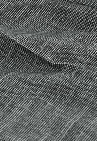 Strukturierten Stoff in Schwarz und Grau mit einem karierten Muster, das feine Webarten und eine glatte Oberfläche zeigt. Wünscht eine subtile Tiefe in den Falten.