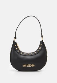 Svart faux läderhandväska med en böjd silhuett, gyllene nitar och blommiga detaljer, med ett övre blixtlås och en axelrem.