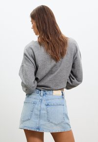 Grå sweatshirt med sjunkna axlar, matchad med en ljusblå denim minikjol med rå kant och två bakfickor.