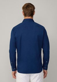 Donkerblauwe lange mouwen shirt van katoen, met een klassieke kraag, geknoopte manchetten en een afgeronde zoom. De textuur is glad en duurzaam.