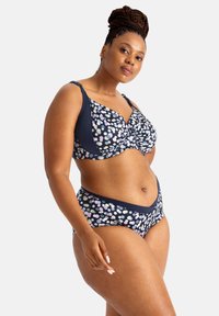 Námornícky bikiny set s bodkovaným vzorom v pastelových farbách. Vrchný diel má skrútený dizajn s nastaviteľnými ramienkami; spodný diel má stredný strih.