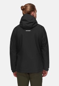 Giacca nera impermeabile con cappuccio, cuciture visibili e logo sul retro. Presenta polsini regolabili e un design ampio.