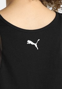 Svart linne med rund halsringning och tunna axelband, med en vit Puma-logotyp av en hoppande katt på baksidan.