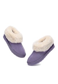 Purple slip-on slippers with a faux fur cuff and soft suede exterior. Flat, textured soles, featuring a rounded toe design.