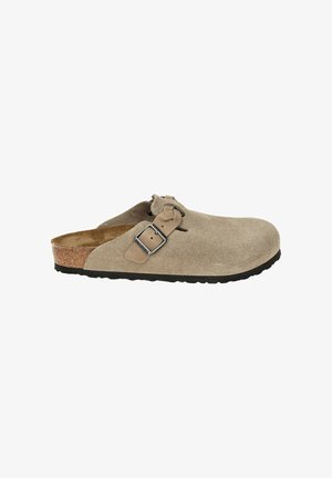 Sabots en suède beige avec un bout arrondi, une sangle ajustable et une boucle, une semelle intermédiaire en liège et une semelle en caoutchouc noir texturé pour une meilleure traction.