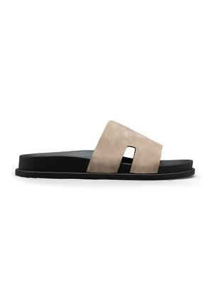 Sandale mule noire avec une large bride beige présentant une découpe rectangulaire, semelle plate et semelle intérieure rembourrée.