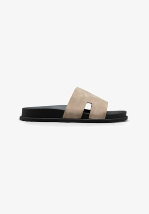 Sandale mule noire avec une large bride beige présentant une découpe rectangulaire, semelle plate et semelle intérieure rembourrée.