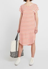 Sukienka w paski z pomarańczowymi i białymi poziomymi paskami, miękka tkanina, zaokrąglony dół, krótkie rękawy, połączona z torbą w paski w czarno-białe wzory.
