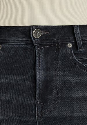 Ciemnoniebieskie dżinsy o klasycznym kroju, z metalowymi detalami w kolorze srebrnym oraz delikatnie przetartą teksturą w pasie i kieszeniach.