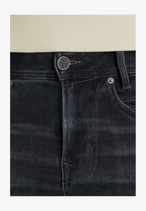 Mørke denim jeans med et klassisk design, sølv hardware og en subtil, slidt texture ved taljen og lommerne.