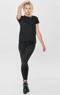 Schwarzes T-Shirt mit kurzen Ärmeln, kombiniert mit schwarzen Skinny-Jeans. Die Schuhwerk besteht aus schwarzen Ankle Boots mit einer Kettenakzent.