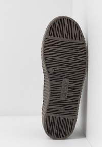 Semelle en caoutchouc noir avec des rainures et des crêtes texturées. Logo "Gabor" imprimé sur le côté. Légèrement usée avec une finition lisse.