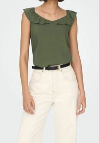 Top senza maniche verde oliva con un collo a volant, abbinato a jeans bianchi alti in vita e una cintura nera. Texture liscia, design casual.