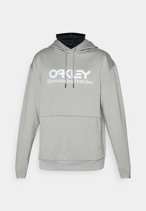 Világosszürke kapucnis felső fekete belső gallérral, fehér "OAKLEY Thermonuclear Protection" logóval és elülső zsebből. Puha anyag, laza szabás.