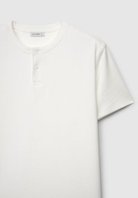 Weißes T-Shirt mit kurzen, gerippten Ärmeln und rundem Ausschnitt, versehen mit zwei Knöpfen und einer weichen Textur. Markenetikett "CALLIOPE" sichtbar.