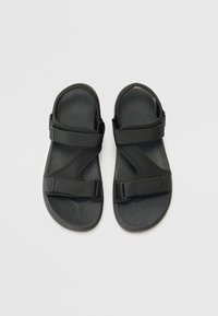 Sorte sportsandaler laget av syntetisk materiale med justerbare stropper, flate såler og en jevn tekstur; minimalistisk design uten dekorasjoner.