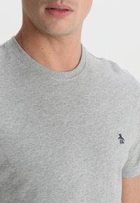 Gray cotton t-shirt with a round neck and short sleeves. Features a small navy penguin logo on the left chest area. Soft texture.
