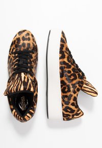 Sneaker con stampa leopardata, lacci neri, parte superiore in pelliccia sintetica, suola bianca e accentuazioni in gomma nera. Punta arrotondata e motivo animale distintivo.