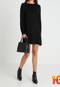 Abito nero a maniche lunghe con scollatura rotonda e leggera svasatura. Abbinato a una borsa nera e stivaletti alla caviglia. Tessuto liscio, design minimalista.