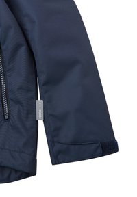 Manica di giacca impermeabile blu navy con una superficie liscia, chiusura con zip e strap in velcro al polsino per una vestibilità regolabile.
